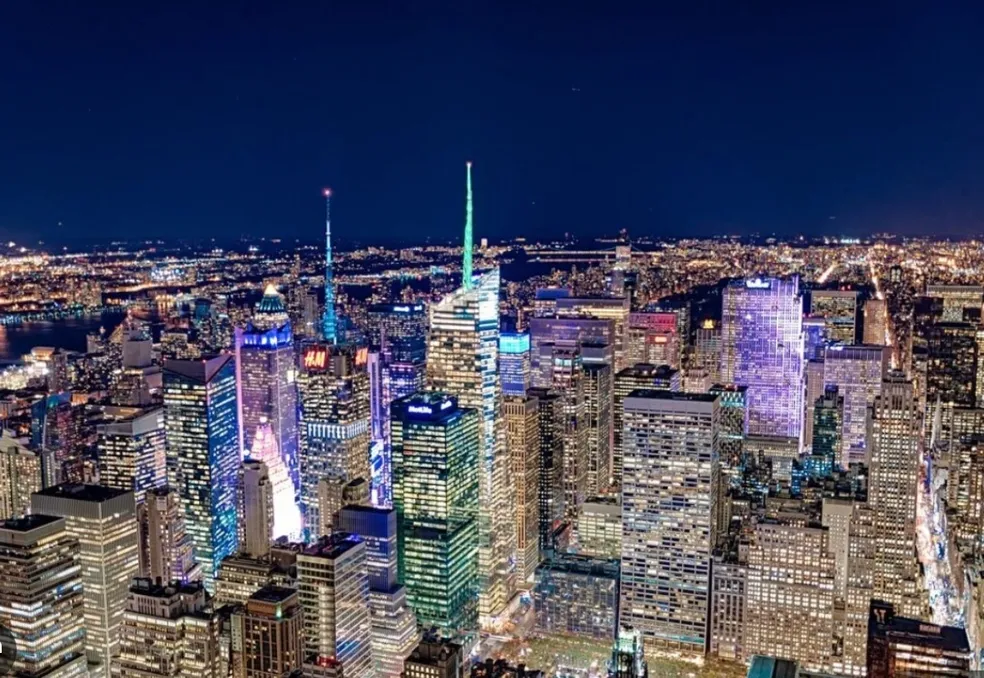 Nighttime cityscape with illuminated skyscrapers and lights.
